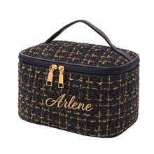 Carica l'immagine nel visualizzatore di Gallery, A rectangular cosmetic bag with a black and gold tweed pattern, featuring a top handle, gold-tone zipper pulls, and a black zipper closure, shown on a plain white background.
