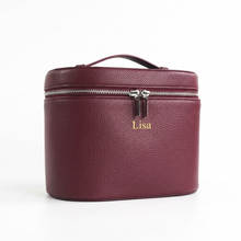 Load image into Gallery viewer, A burgundy cosmetic case with a top handle and zipper closure, shown on a white background with dimension lines and text indicating measurements. The case has a small gold logo on the front.

