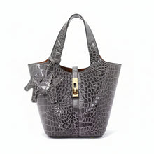 Carica l'immagine nel visualizzatore di Gallery, Gray crocodile-embossed handbag with gold clasp on a white background
