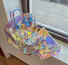 Load image into Gallery viewer, Travellers Hat Boutique holographic clear tote bag with colorful handles displayed on windowsill
