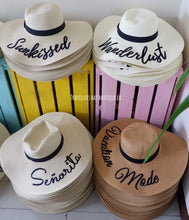Cargar imagen en el visor de la galería, Wholesale floppy sun hats with wide brims and black ribbon bands featuring embroidered words from Travellers Hat Boutique
