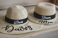 Cargar imagen en el visor de la galería, Custom prenuptial hat set with Bride and Groom straw hats featuring black bands and personalized names
