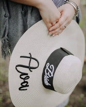 Cargar imagen en el visor de la galería, Custom prenuptial hat set with bride embroidery and wide brim held by person wearing bracelets
