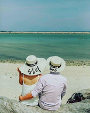 Cargar imagen en el visor de la galería, Bride and groom wearing custom prenuptial hat set with names on a beach by the ocean
