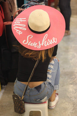 Woman wearing a hand-painted straw hat with pink brim and Hello Sunshine text in white