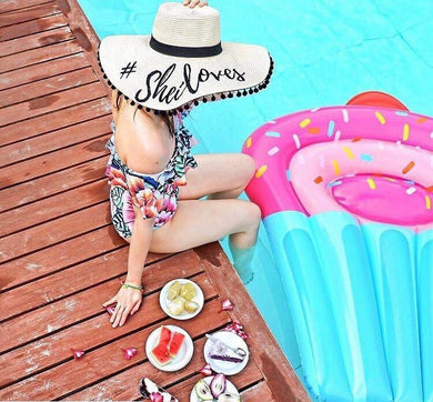 Custom floppy hat with pompoms by Travellers Hat Boutique worn by woman sitting poolside